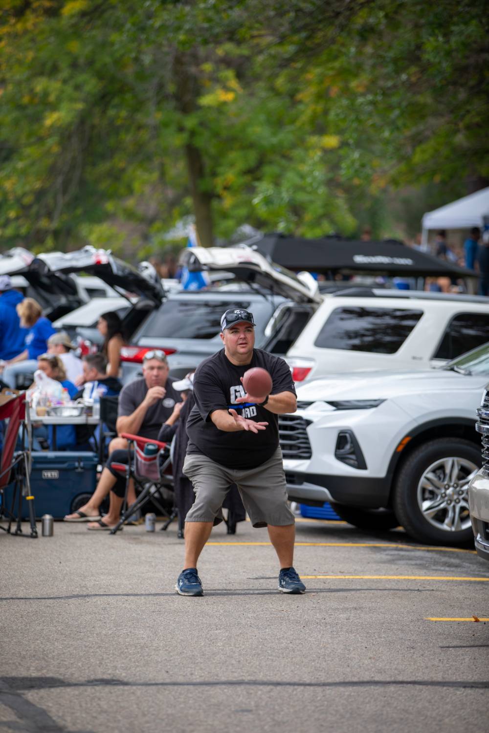 Attendee catches football in parking lot during Family Day tailgate.